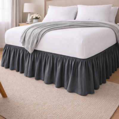 Impeccable hotel bed featuring a dark gray ruffled bed skirt and crisp white linens.